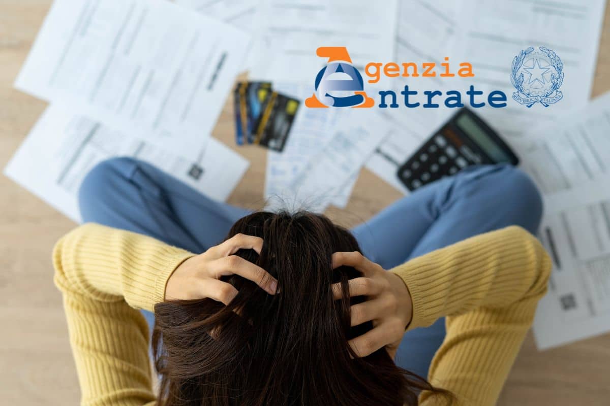 donna disperata con pile di documenti davanti e logo agenzia delle entrate