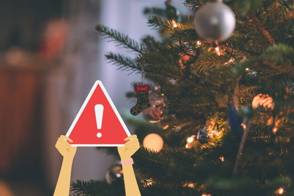 albero di natale e due mani che tengono cartello attenzione