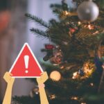 albero di natale e due mani che tengono cartello attenzione