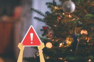 albero di natale e due mani che tengono cartello attenzione