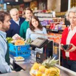 signora guarda nel portafogli alla cassa di un supermercato
