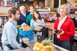 signora guarda nel portafogli alla cassa di un supermercato