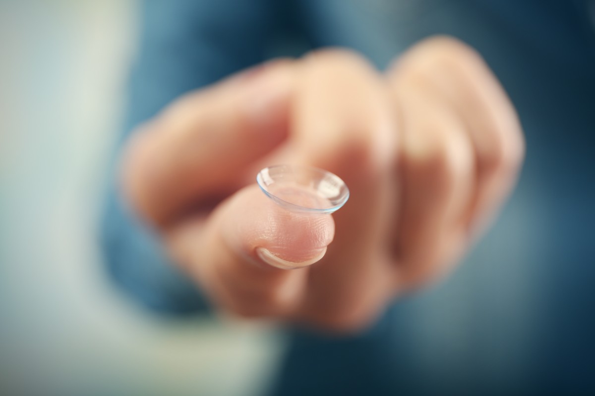 persona con in mano una lente a contatto
