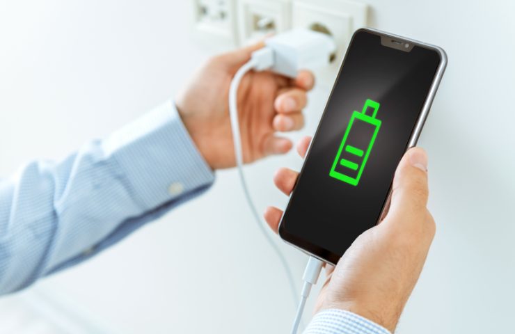 Smartphone in ricarica tra due mani