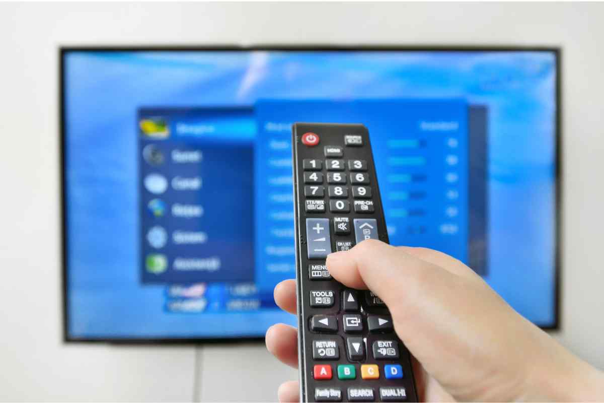 Telecomando in una mano e smart tv sullo sfondo