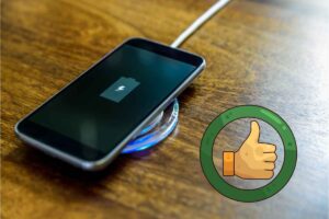 Smartphone su base di ricarica poggiata su tavolo di legno