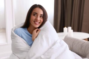 Ragazza contenta avvolta da un piumone in casa