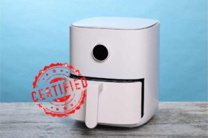 Friggitrice ad aria bianca con cestello aperto su tavolo di legno