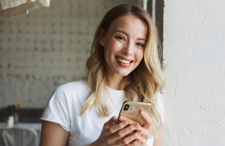 Donna sorridente con smartphone tra le mani