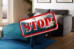 divano letto in casa con scritta stop in evidenza