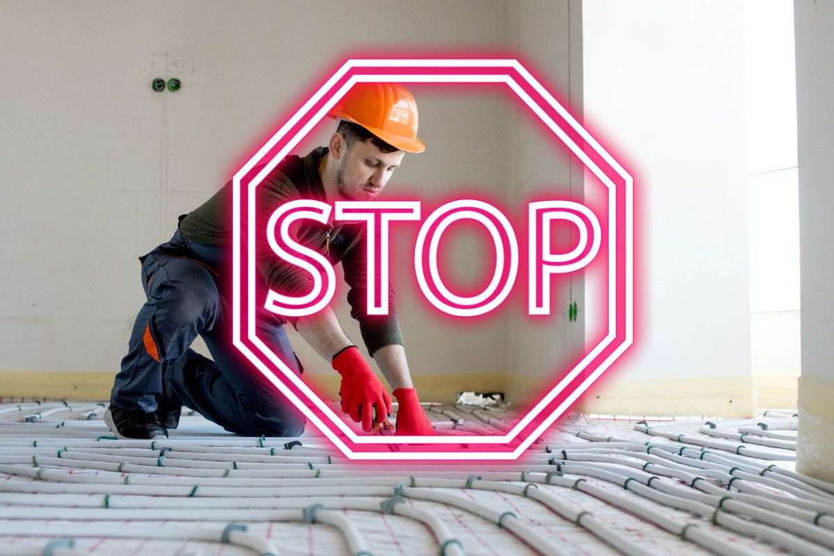 tecnico installa riscaldamento a pavimento scritta stop in evidenza