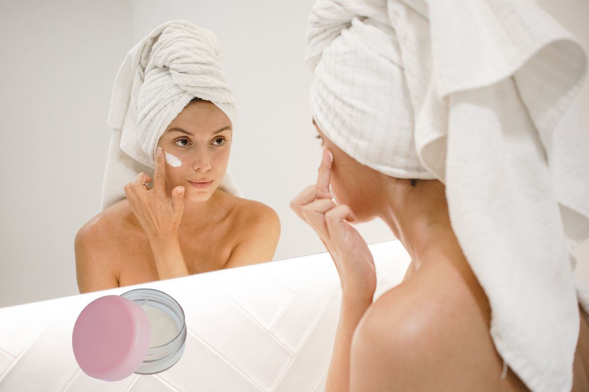 donna allo specchio che applica crema sul viso