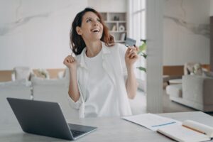 donna che esulta con pc davanti e carta di credito in mano
