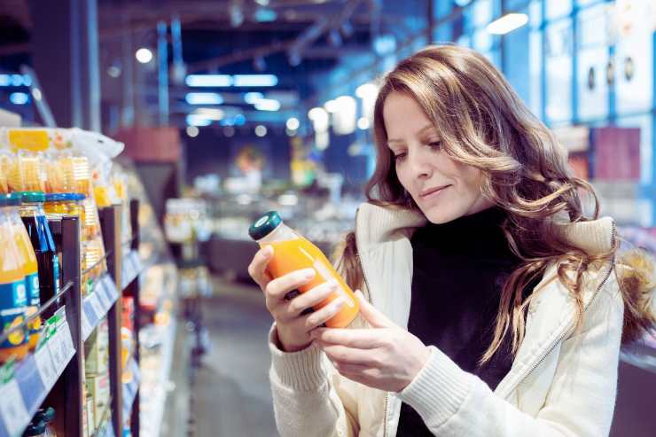 donna al supermercato consulta etichetta prodotto