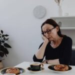 donna triste poggiata a un tavolo
