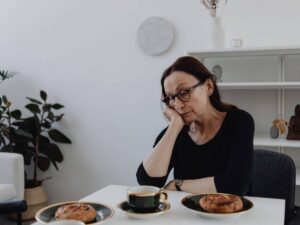 donna triste poggiata a un tavolo