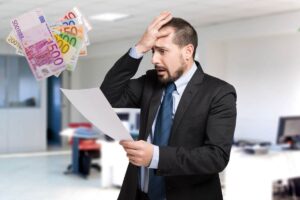 uomo disperato che legge busta paga, banconote euro in evidenza